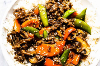Homemade ground beef stir fry with colorful vegetables served over steamed rice in a bowl
