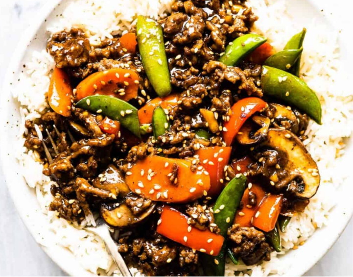 Homemade ground beef stir fry with colorful vegetables served over steamed rice in a bowl