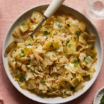 Tender braised cabbage cooked with onions, garlic, butter, and herbs in a savory broth, garnished with fresh parsley.