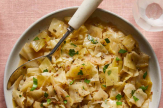 Tender braised cabbage cooked with onions, garlic, butter, and herbs in a savory broth, garnished with fresh parsley.