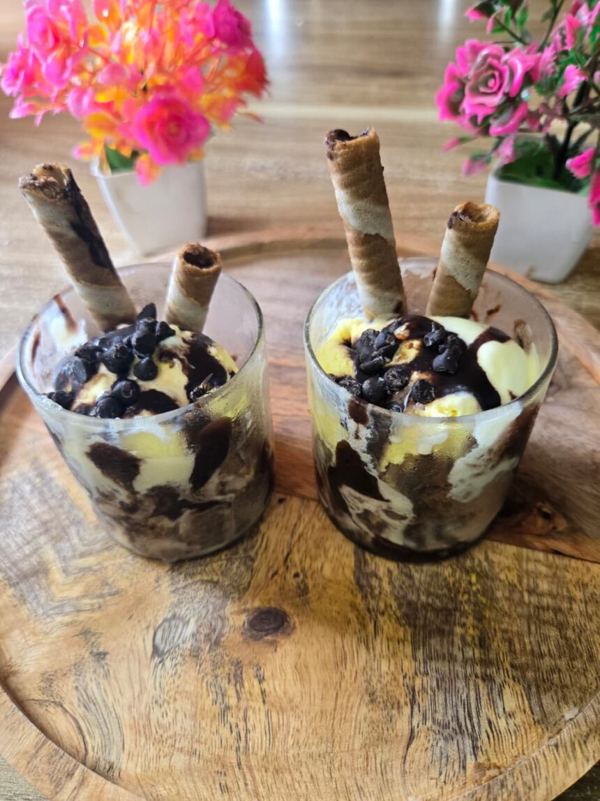 Classic homemade ice cream sundae topped with chocolate sauce, whipped cream, colorful sprinkles, and a cherry